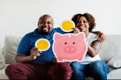 Smiling couple with cutout of piggy bank and coins.